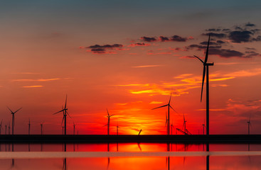 Fototapeta na wymiar Wind farm at the sunset; wind turbines on the burning sky; background of wind farm