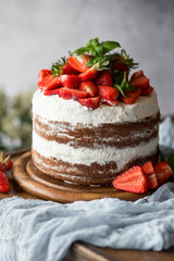 Naked cake with cream, decorated with strawberry and mint. Chocolate cake.