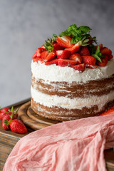 Naked cake with cream, decorated with strawberry and mint. Chocolate cake.