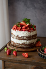 Naked cake with cream, decorated with strawberry and mint. Chocolate cake.
