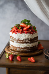 Naked cake with cream, decorated with strawberry and mint. Chocolate cake.