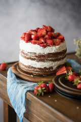 Naked cake with cream, decorated with strawberry and mint. Chocolate cake.