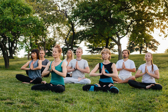 A group of people do yoga in the Park at sunset. Healthy lifestyle, meditation and Wellness