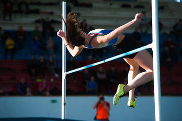 Woman jumping over bar at athletics meeting