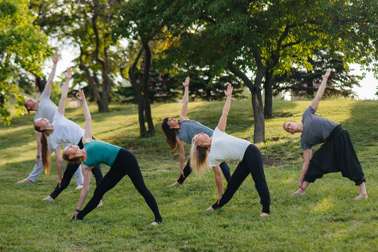 A group of people do yoga in the Park at sunset. Healthy lifestyle, meditation and Wellness