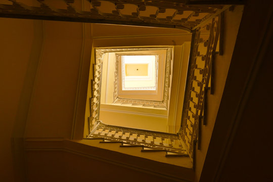 Spiral Stairs in an Old House with Yellow Tones Because of the Sun on the Roof - Powered by Adobe