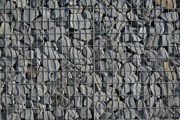 Decorative gabion fence is made of natural stone and metal mesh.