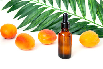 Bottle of peach oil, decorated with peaches on white background.