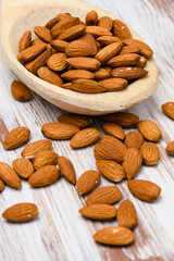 Close-up of dried almonds in a wooden spoon on a wooden background. 