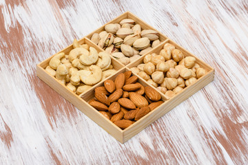 Close-up of pistachios in a wooden box. Assortment of nuts in the background.