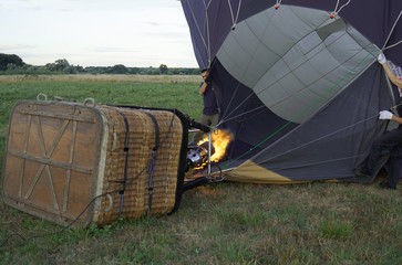 Obraz premium Inflating a balloon lying on the grass with burning air. A fire burning inside the ball 