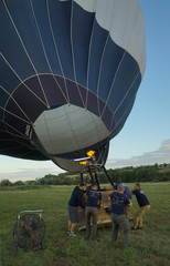 Obraz premium Inflating a balloon lying on the grass with burning air. A fire burning inside the ball 
