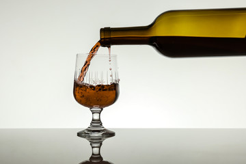 wine is poured into a glass from a bottle on a white background
