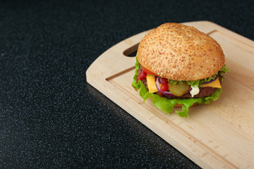 burger is on cutting board on black background