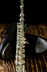 details of tap shoe and silver cross flute, black background, short depth of field.