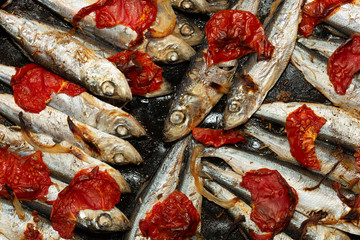 Baltic herring baked in a baking tray with tomatoes and onions.