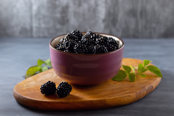 Fototapeta na wymiar Close-up of fresh blackberries in bowl on rustic board on table