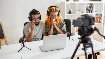 Sad movie. Couple of bloggers, young man and woman looking sad, crying while watching something on laptop, recording reaction video blog or vlog
