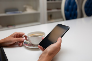 Woman is holding smartphone and drink coffee 