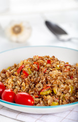 Buckwheat pilaf (pilav) with vegetable in dish on wooden background.