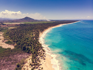 Aerial drone view of paradise beach with palm trees, blue water and mountains at the Esmeralda beach, Miches, Dominican Republic  