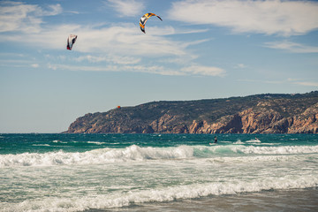 Guincho beach sea with surfers doing kitesurf and with the blue sky in the background, Cascais, Portugal