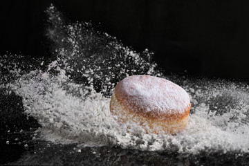 Berliner donut with jam stuffed falls into flour.