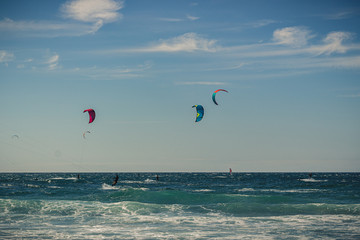 Guincho beach sea with surfers doing kitesurf and with the blue sky in the background, Cascais, Portugal