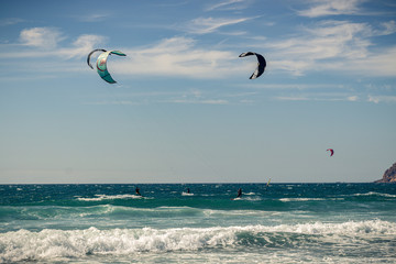 Guincho beach sea with surfers doing kitesurf and with the blue sky in the background, Cascais, Portugal