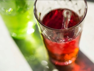 zwei Gläser mit grünem und rotem Longdrink im Sonnenlicht werfen bunte Schatten