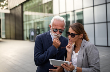 Two business people looking at tablet outdoor