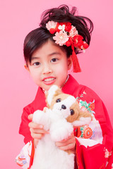 犬のぬいぐるみを持つ振袖姿の女の子