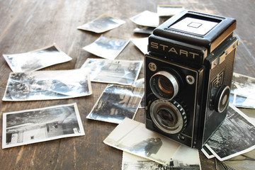 Polski powojenny aparat fotograficzny, obok rozrzucone czarno-białe zdjęcia - obrazy, fototapety, plakaty