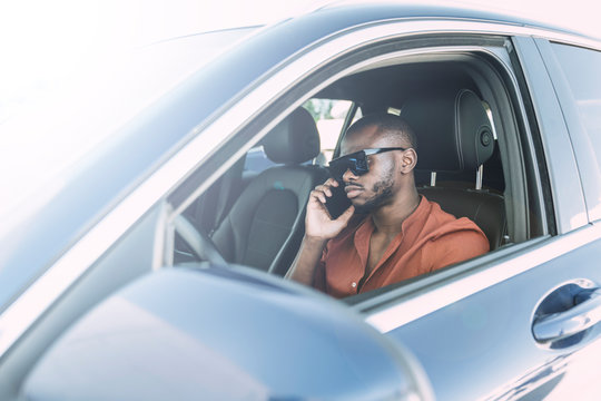 Young Black Man Making Phone Call While Is Driving Car