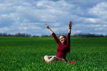Naklejka na ściany i meble Young successful woman is sitting on green grass with a laptop in her hands. Rest after a good working day. Work on the nature. Student girl working in a secluded place. Workplace in nature