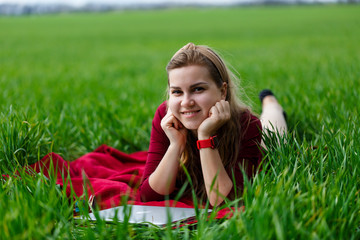 Young beautiful woman student with a laptop lies on the grass. Work outdoors.