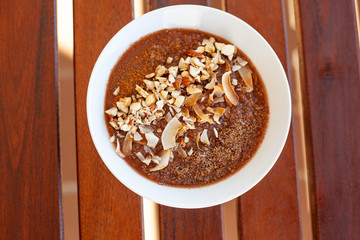Breakfast bowl with quinoa, banana, coconut, cocoa, walnuts served on wooden table