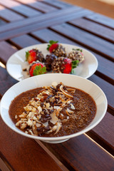 Breakfast bowl with quinoa, banana, coconut, cocoa, walnuts served on wooden table