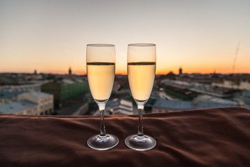 Two glasses of champagne on the background of city roofs at sunset
