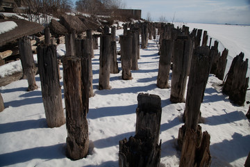 Fototapeta na wymiar Rotten piles frozen in ice on the old pier