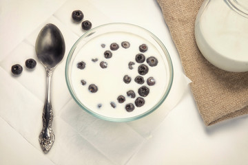blueberry berry in a glass deep plate with milk on a white table. breakfast concept, healthy food, vitamins.