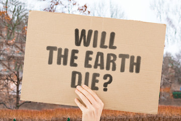 The question " Will the Earth die? " on a banner in men's hand with blurred background. The end of the world. Apocalypse. Life. Universe. Humanity. Problem. Hazardous. Dangerous. Science