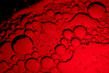 Abstract bubbles in liquid with red background. Different sized and shaped bubbles.
