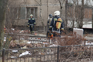 Russian rescuers at the site of the collapse of the wall of a brick apartment building. Destroyed car