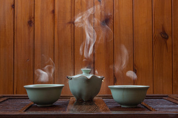 Traditional chinese porcelain tea cups with cloud of steam on wooden background