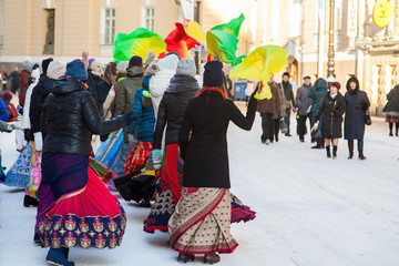 Naklejka premium Girls in winter jackets dance on a snowy street with fans. Hare Krishna sectarians