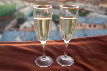 Two glasses of champagne on the background of city roofs at sunset