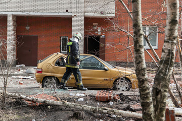 Fototapeta premium Russian rescuers at the site of the collapse of the wall of a brick apartment building. Destroyed car