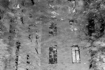 Vintage house windows reflected in a muddy puddle