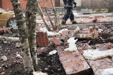 Russian rescuers at the site of the collapse of the wall of a brick apartment building. Destroyed car